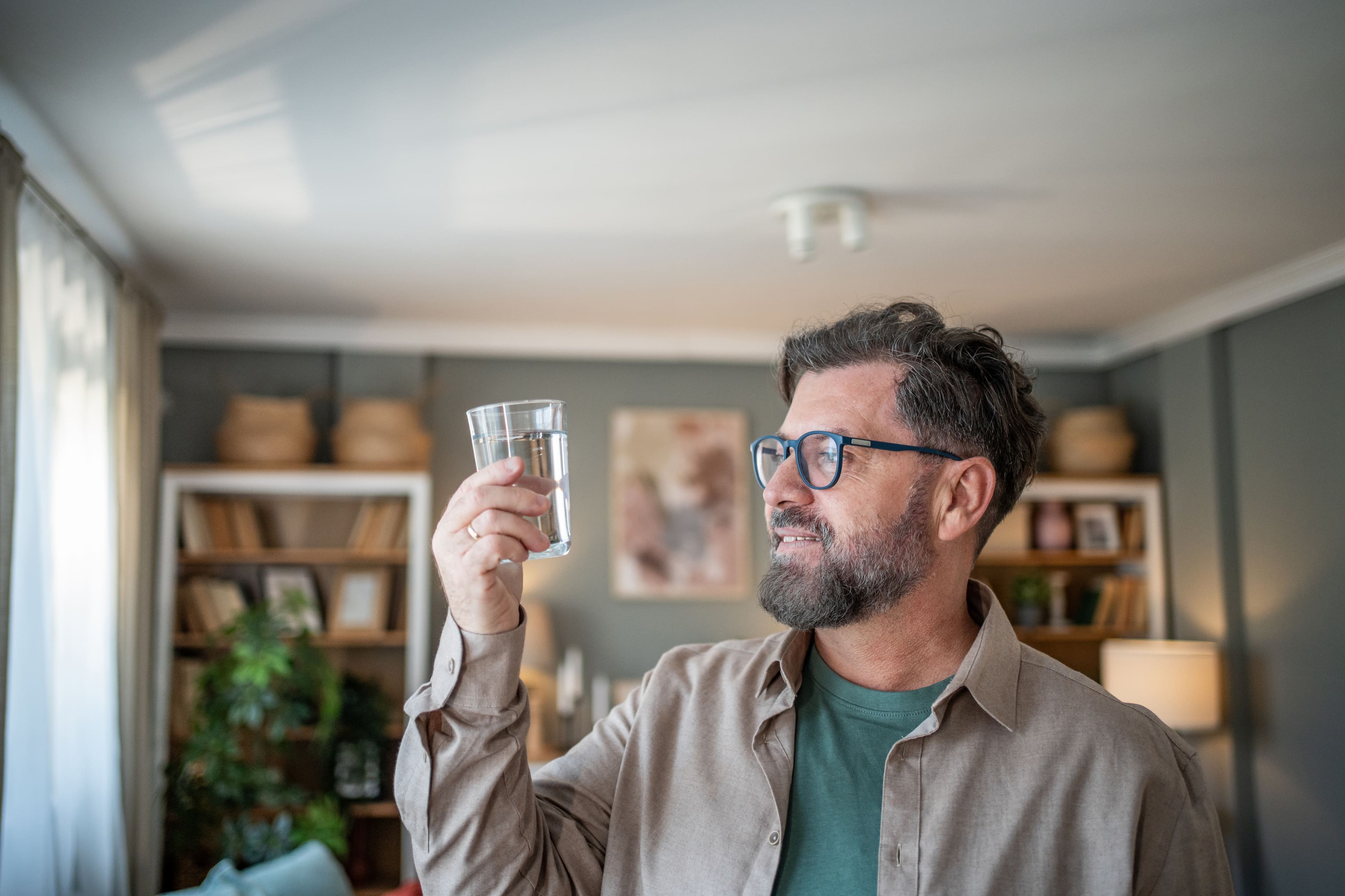 Mann betrachtet Wasserglas in seiner Hand